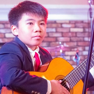 Boy Playing a Classical Guitar on Stage